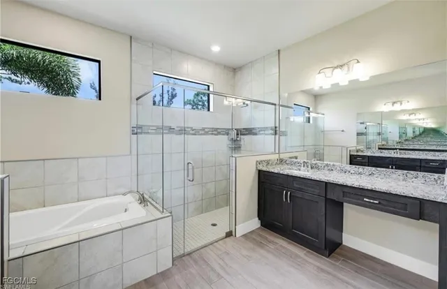 a bathroom with a granite countertop sink mirror and bathtub