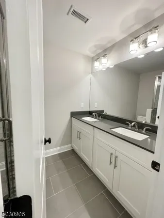 a spacious bathroom with a double vanity sink a mirror and a shower