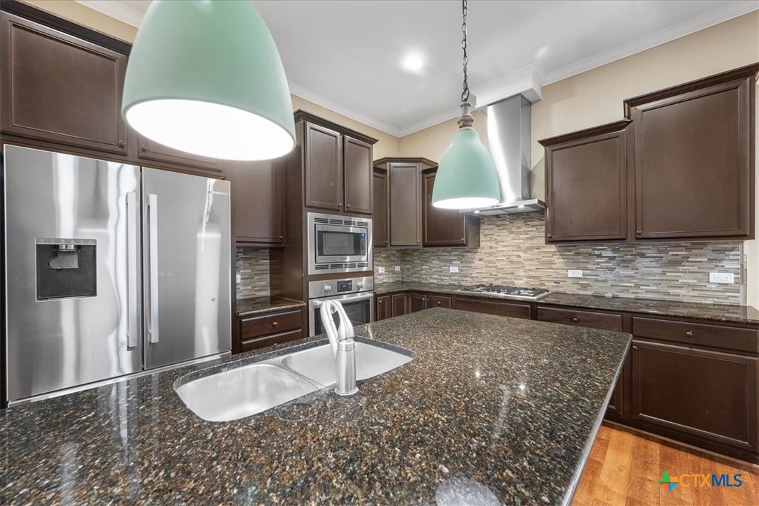 1009 Highknoll Lane Georgetown, TX 78628 - Photo 11 of 38 a kitchen with kitchen island granite countertop a sink stainless steel appliances and cabinets