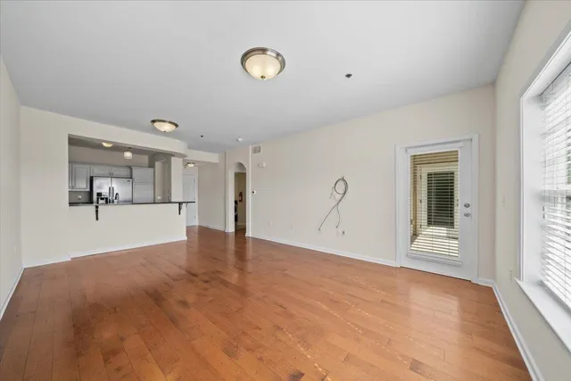 a view of an empty room with a window and wooden floor