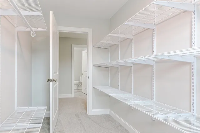 a view of an empty walk in closet with kitchen view