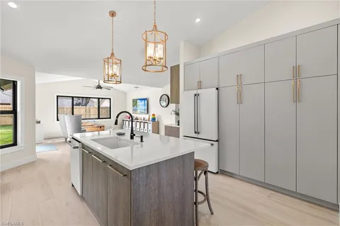 a kitchen with stainless steel appliances granite countertop a sink a center island and a wooden floor