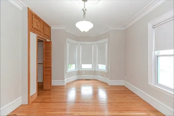 a view of empty room with wooden floor and fan