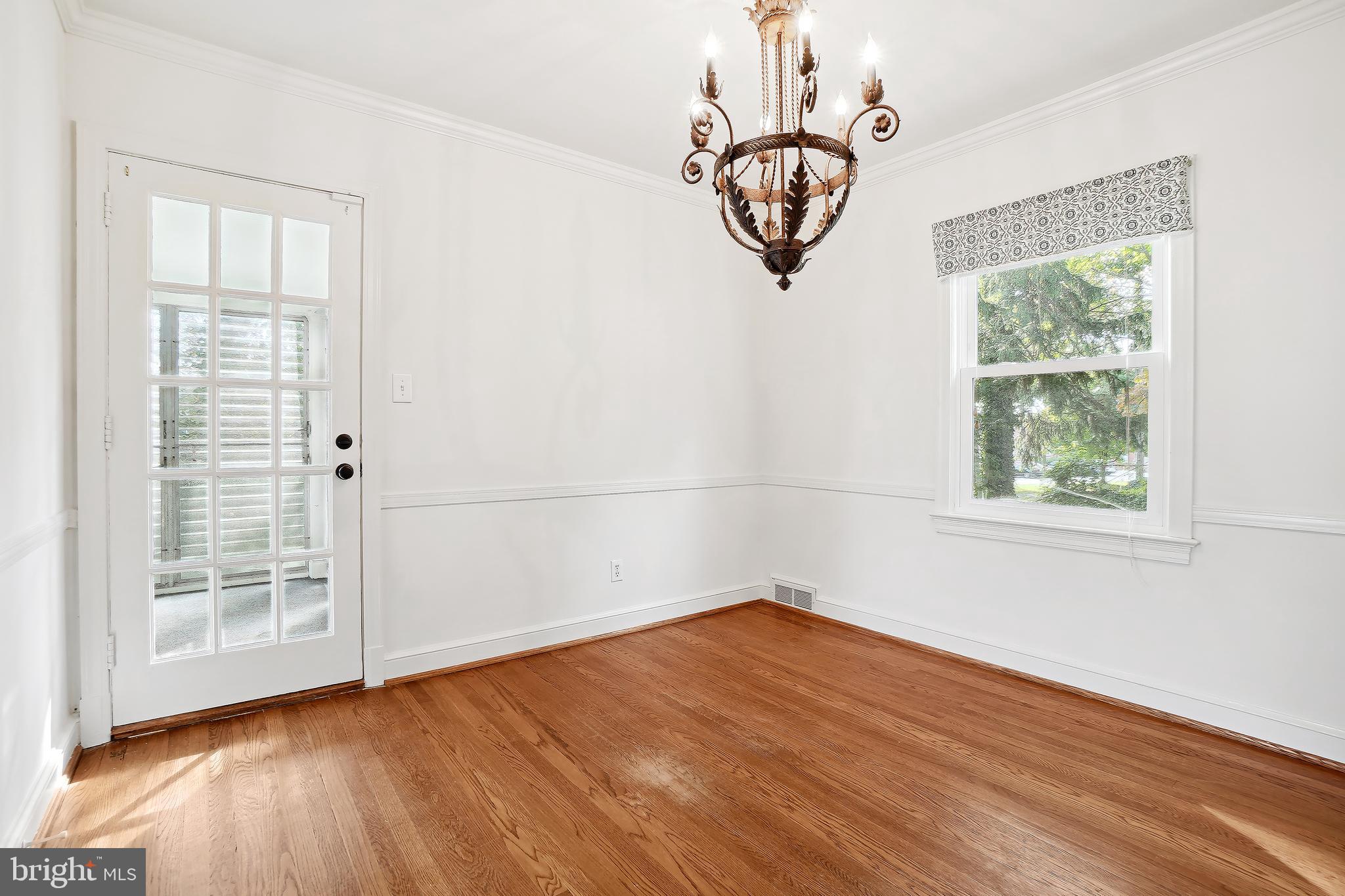 7000 Exeter Road Bethesda, MD 20814 - Photo 9 of 31 an empty room with wooden floor a chandelier fan and windows