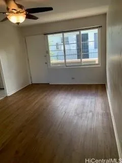 a view of an empty room with wooden floor and a window