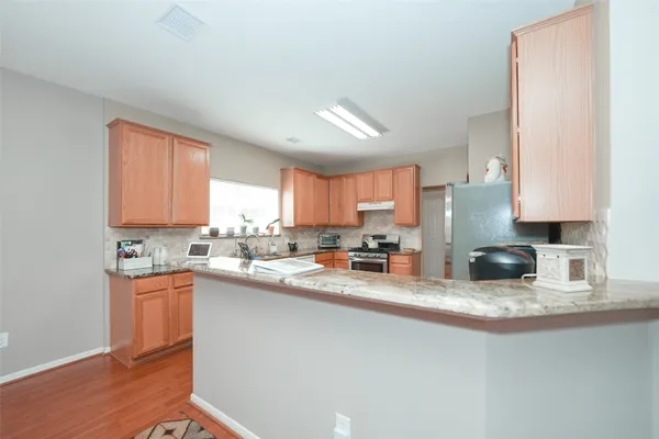 a kitchen with stainless steel appliances granite countertop a sink a stove a refrigerator a cabinets and wooden floor