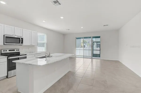 a large white kitchen with granite countertop a stove top oven a sink with dishwasher and cabinets