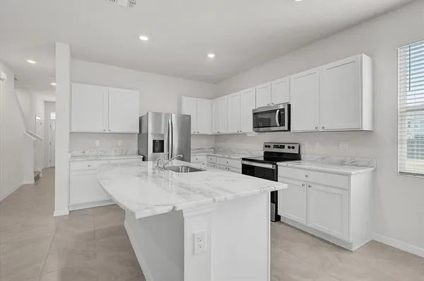 a kitchen with a sink a microwave a refrigerator and cabinets