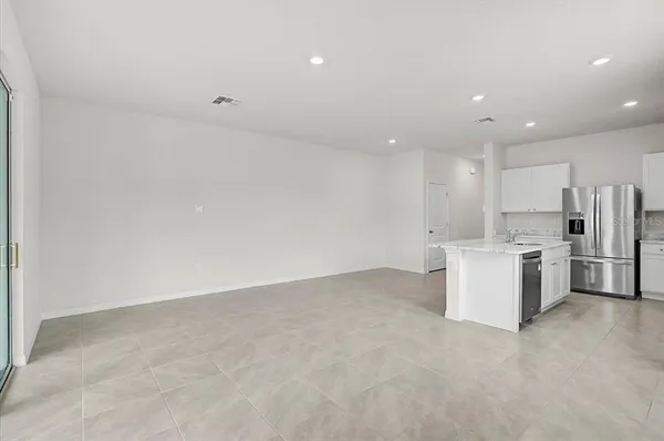 a view of kitchen with stainless steel appliances refrigerator stove microwave and white cabinets