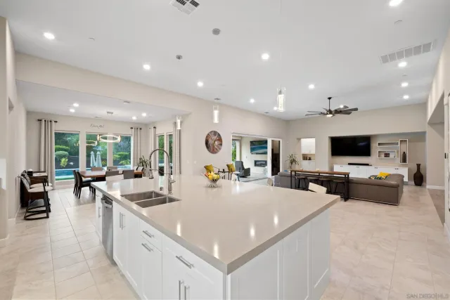 a kitchen with a dining table chairs sink and white cabinets