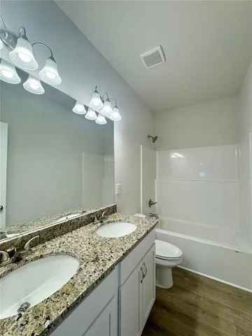a bathroom with a granite countertop sink a toilet and a large mirror