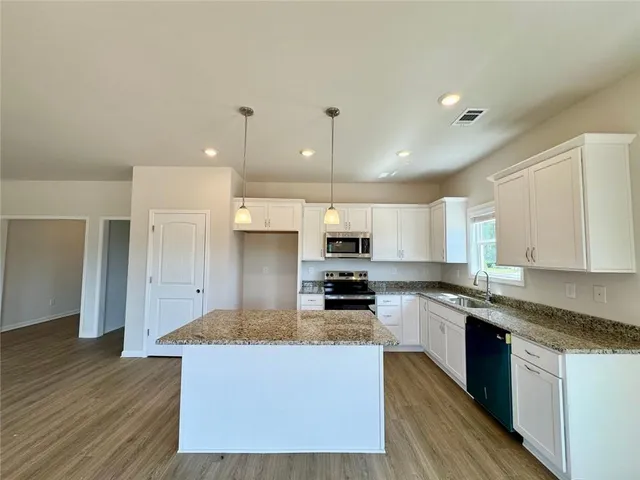 a large kitchen with stainless steel appliances granite countertop a stove a sink and a refrigerator