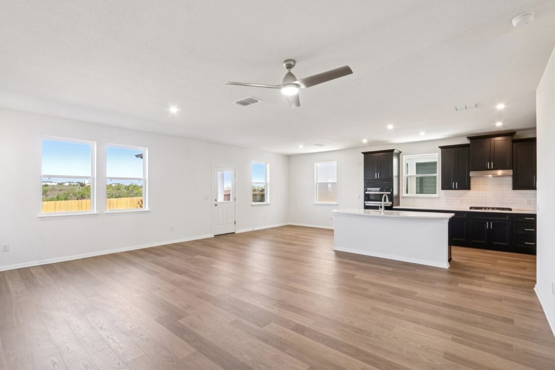 11224 Zip Cochise Way Manor, TX 78653 - Photo 24 of 40 a view of an empty room and kitchen with wooden floor and window