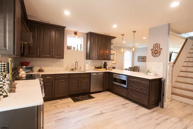 a large kitchen with a large counter top space a sink stainless steel appliances and cabinets