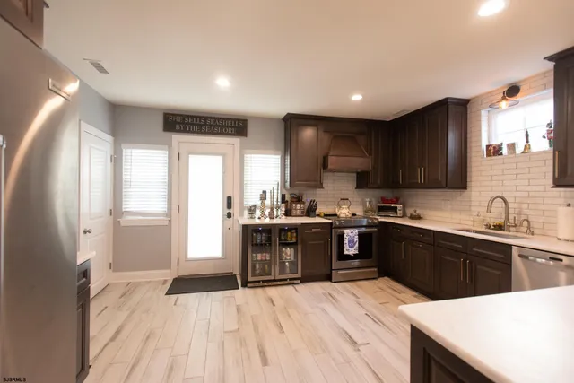 a kitchen with stainless steel appliances granite countertop a sink a refrigerator and chairs