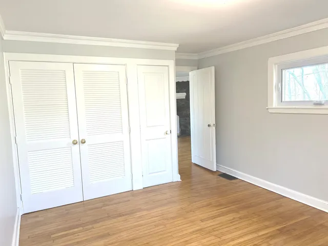 a room with wooden floor and furniture next to a window