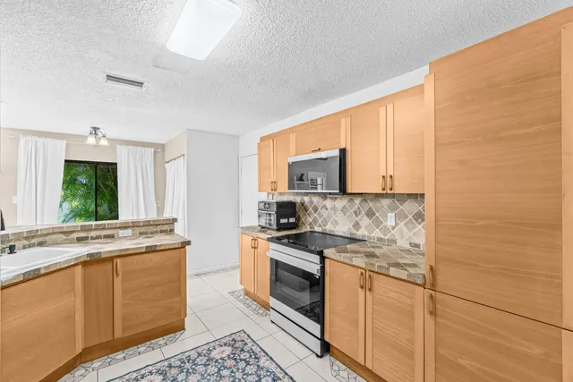 a kitchen with stainless steel appliances granite countertop a stove a sink and a microwave
