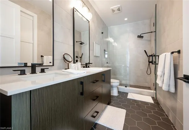 a bathroom with a double vanity sink a toilet and a mirror