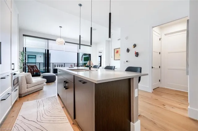 a kitchen with stainless steel appliances kitchen island granite countertop a sink a counter space and living room view