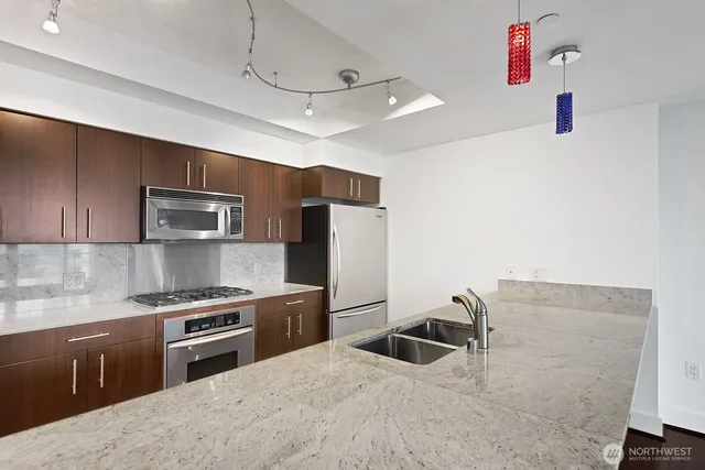 a kitchen with stainless steel appliances granite countertop a sink and a stove