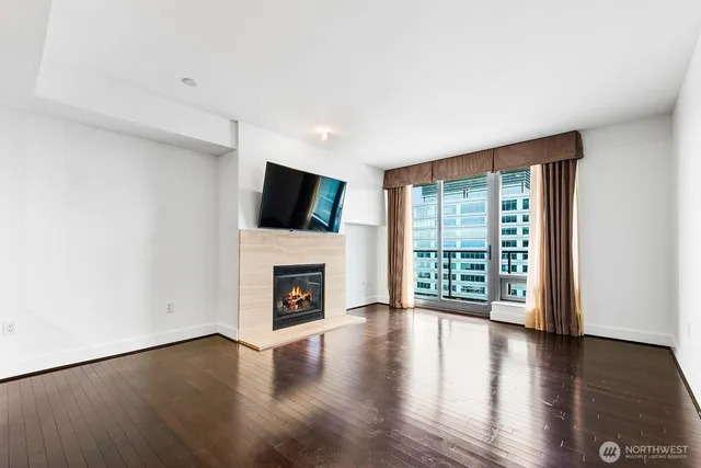 a living room with stainless steel appliances a fireplace a flat screen tv and view kitchen