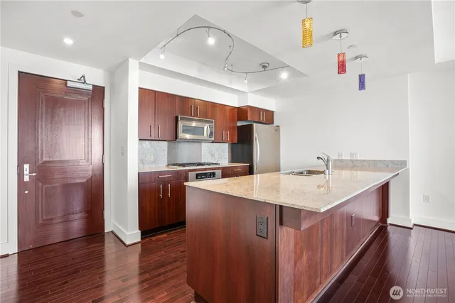 a kitchen with a sink a refrigerator and wooden floor