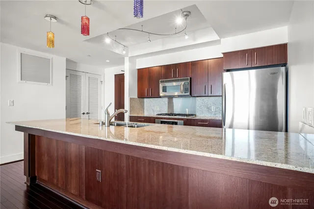 a large kitchen with a large counter top stainless steel appliances and cabinets