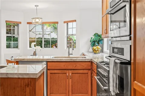 a kitchen with stainless steel appliances granite countertop a sink a stove and a wooden cabinets