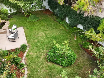 a backyard of a house with a lot of flower plants and wooden fence