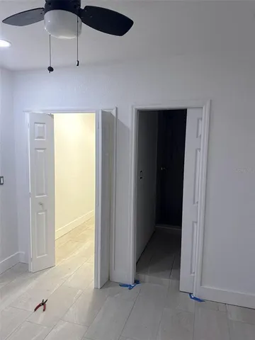 an empty room with a window and chandelier fan
