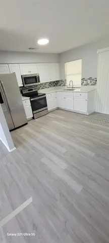 a kitchen with stainless steel appliances wooden floor and a sink