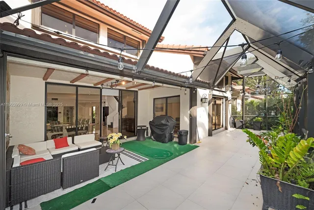 a view of a patio with table and chairs potted plants and floor to ceiling window