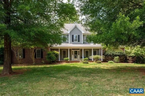 front view of a brick house with a large window and potted plants