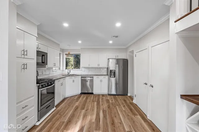 a kitchen with a refrigerator a sink and dishwasher with wooden floor