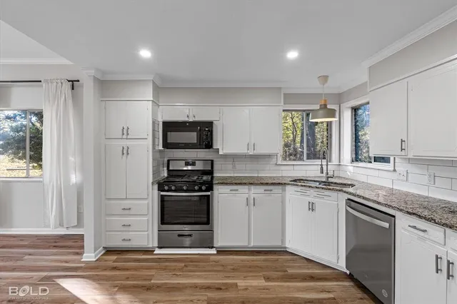 a kitchen with stainless steel appliances granite countertop a stove a sink and a microwave