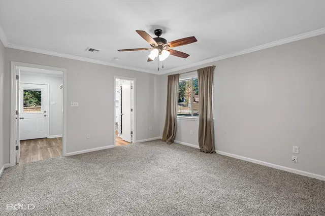 a view of a livingroom with a ceiling fan & windows