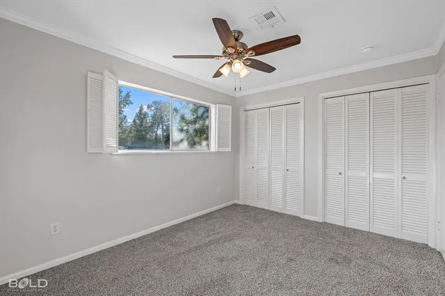 a view of a livingroom with a ceiling fan & windows