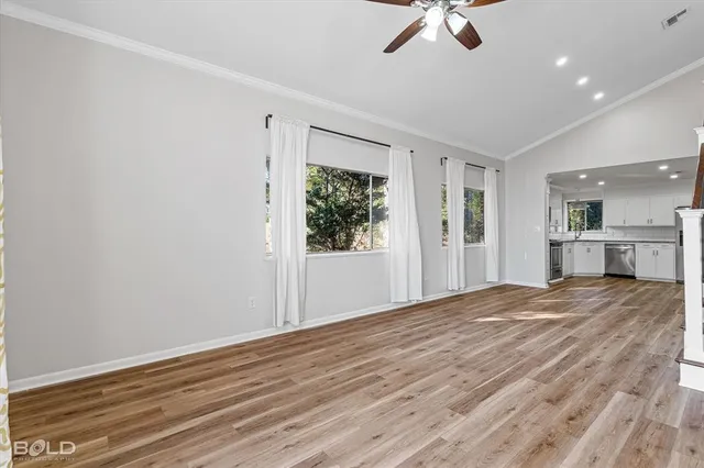 a view of an empty room with window and wooden floor