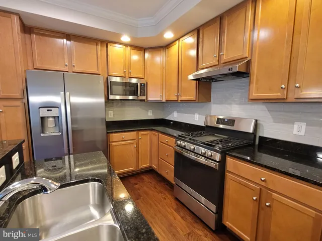 a kitchen with granite countertop a sink stainless steel appliances and cabinets