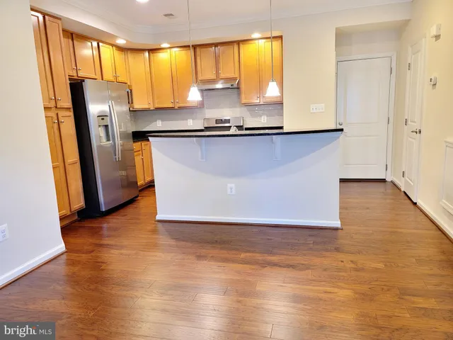 a view of kitchen with stainless steel appliances granite countertop a sink and a refrigerator