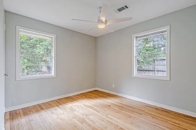 a view of empty room with wooden floor and fan