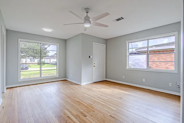 a view of an empty room with wooden floor and a window