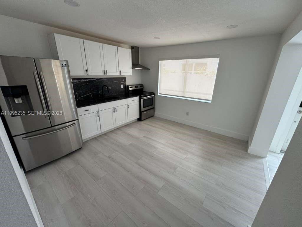 230 East 56th Street, Unit A Hialeah, FL 33013 - Photo 12 of 25 a kitchen with granite countertop white cabinets and refrigerator