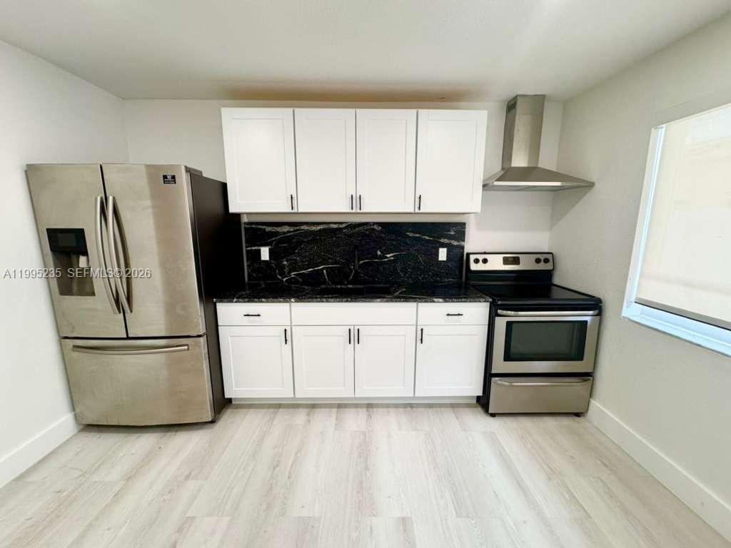 230 East 56th Street, Unit A Hialeah, FL 33013 - Photo 5 of 25 a kitchen with a refrigerator and white cabinets