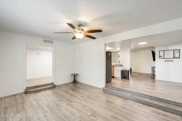an empty room with wooden floor and a ceiling fan