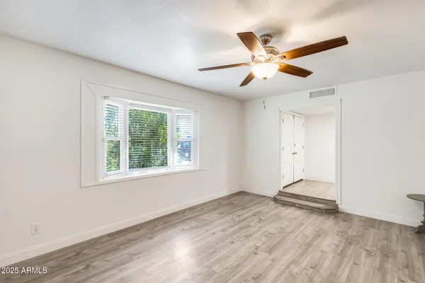 a view of an empty room with window and wooden floor