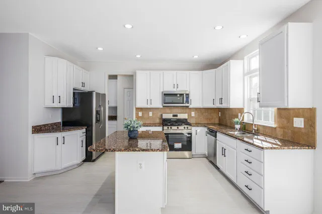 a kitchen with stainless steel appliances a refrigerator sink stove and white cabinets