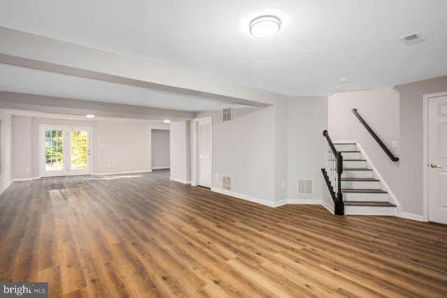 a view of an empty room with wooden floor and window