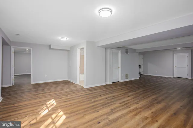 a view of an empty room with wooden floor and closet
