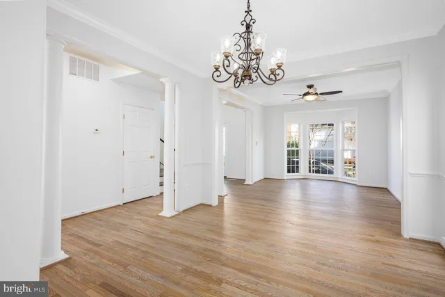 a view of an empty room with wooden floor and windows
